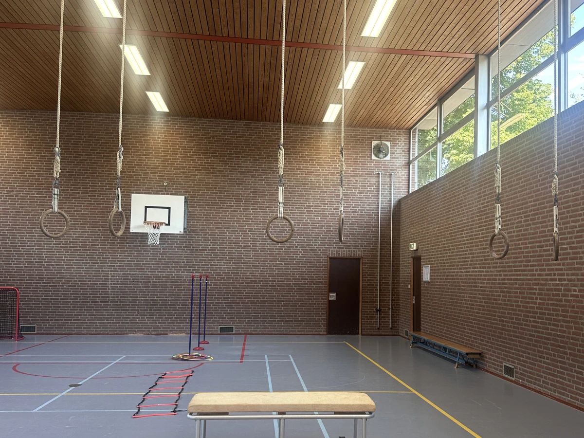 Ruime, rustige gymzaal van Veilige Haven met ringen, klimtouwen en oefenmateriaal
